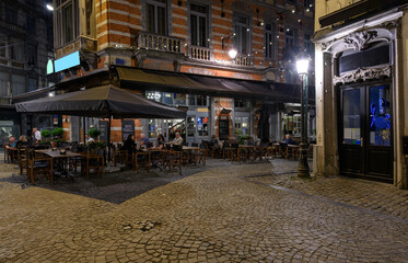 Cozy old street with tables of cafe in center of Brussels, Belgium. Night cityscape of Brussels (Bruxelles). Architecture and landmarks of Brussels.