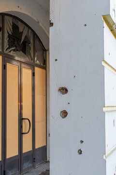 Irpin, Ukraine - 07 March 2026: View of a building facade scarred by destruction, where shattered glass contrasts with the stark grey wall riddled with bullet holes.