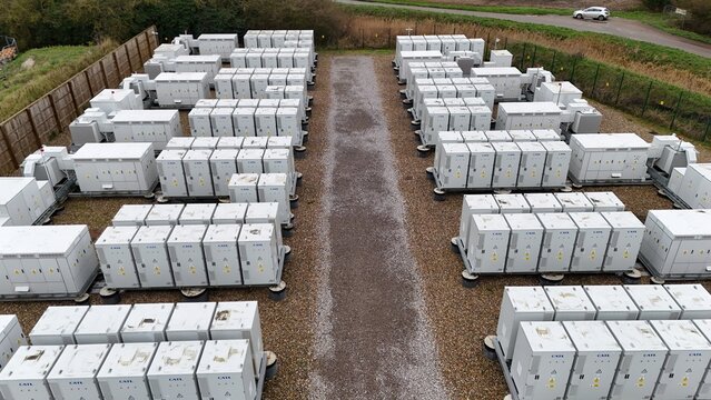 Aerial view of rows of battery energy storage systems BESS casting long shadows in the afternoon light, Burwell, United Kingdom.