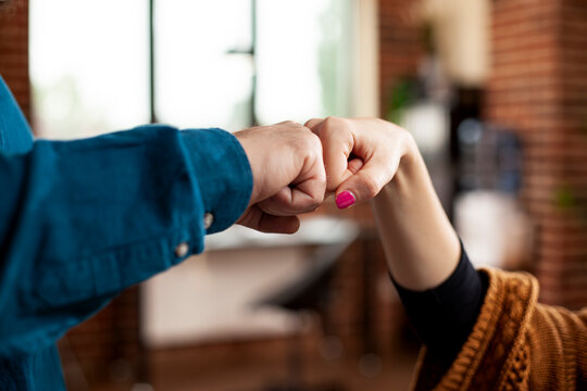 Closeup of hands exchanging fist bump in office, symbolizing unity and cooperation between partners. Two professional individuals making hand gestures, representing successful business collaboration.