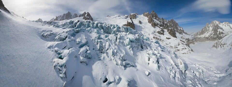Aerial view of the stark contrast between the jagged, rocky peaks and the smooth, icy expanse of Vallee Blanche Glacier, Chamonix-Mont-Blanc, Auvergne-Rhone-Alpes, France.