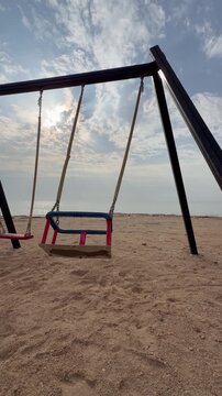 A quiet winter beach in Sila shows wooden swing seats on soft sand, facing gentle waves near the Abu Dhabi&ndash;Saudi border.