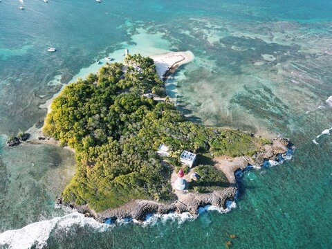 Aerial view of a lush island paradise with vibrant turquoise waters meeting rocky shores and dense tropical foliage, Guadeloupe, Guadeloupe.