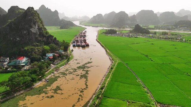 Aerial view of cargo barges on a river in ninh binh with karst mountains and rice paddies in the background