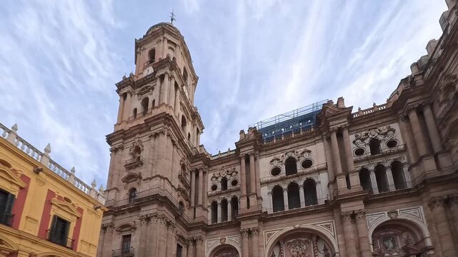 Malaga Cathedral Tower and Ornate Stone Facade Overlooking Colorful City Buildings Under Dramatic Sky, Spain