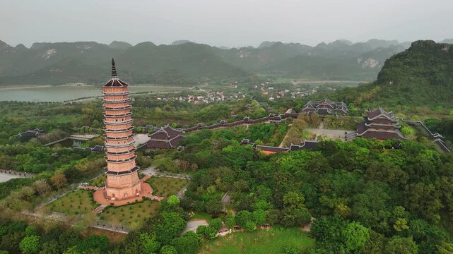 Aerial view of bai dinh pagoda and tall stupa in a lush valley with mountains and lake in ninh binh, vietnam
