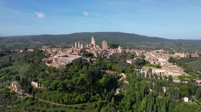Aerial view of the medieval towers of San Gimignano rising above the Tuscan landscape, a symphony of terracotta roofs and verdant hills, San Gimignano, Tuscany, Italy.