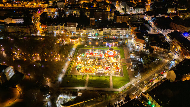 Aerial drone view of the festive Christmas market at Place Rapp in Colmar, France, with carousel and night illuminations.
