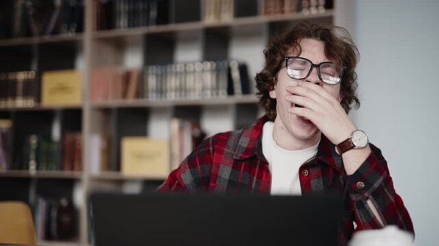 Tired student yawning while studying in a university library