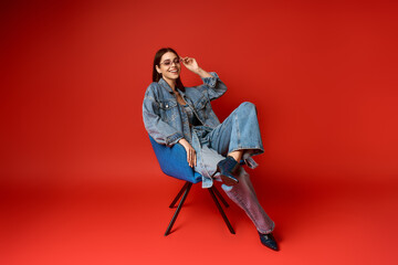Obraz premium Stylish young woman in denim outfit poses confidently in studio setting