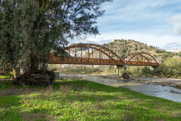 Obraz premium Pedestrian bridge (tied arch) crossing the Guadalhorce river near Alora in Andalusia, Spain; the river is low but ihas a history of sudden floods. 