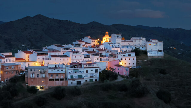 Illuminated streets and Ermita del Calvario in Alora, Andalusia, Spain, under a cloudy sky at sunset in winter