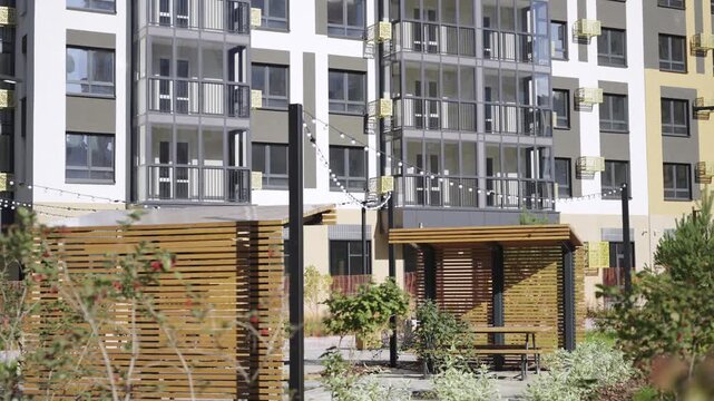 Wooden gazebos in yard of residential complex in city district. Condominium buildings with arbors and lamp garlands in dwelling block
