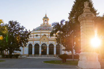 Seville, Spain. The domed pavilion of the Casino de la Exposicion stands at center, its tiled cupola, ornate stucco, and arched windows visible in warm late afternoon light.