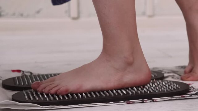 Sadhu massage. Yoga board. Woman developing endurance barefoot standing on sharp nails on mat spiritual growth mental health.