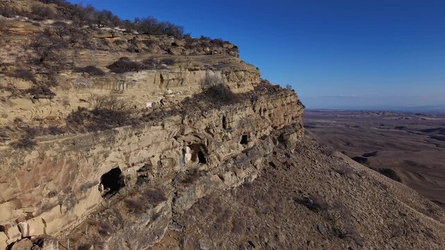 Abandoned caves carved into a rugged cliff, standing as a powerful symbol of solitude, forgotten history, and the passage of time. evokes mystery and the weight of the past.