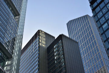 Fototapeta premium View of modern business district skyscrapers glass facades and geometric patterns under a clear blue sky.