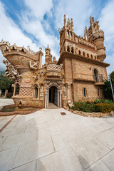 Obraz premium Elaborate brick and stone monument in Benalmadena, Malaga shows arches, ship prow, minaret like towers, nautical reliefs, and a fountain, honoring Christopher Columbus.