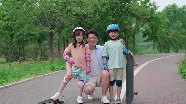 Dad taking kids skateboarding in the park