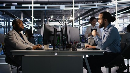 Data center technician discussing with coworker while doing AI software updates. Server room IT...