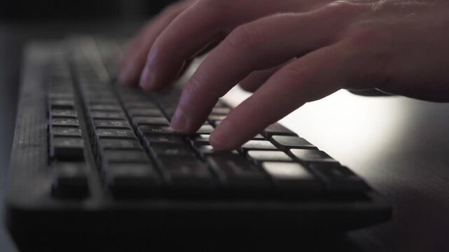 Hands typing on a dusty keyboard on a dark table