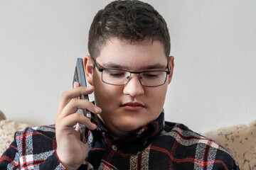 teenager in glasses talks on a smartphone, engaged in a conversation. © diy13