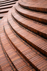 Sunlit curved brick staircase abstract design with warm golden light at sunset, highlighting architectural patterns and shadows.