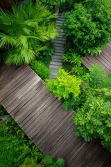 Fototapeta premium Intersecting wooden decks weaving through lush greenery with palms shrubs and varied foliage forming a layered garden pathway viewed from above in a compact tropical courtyard