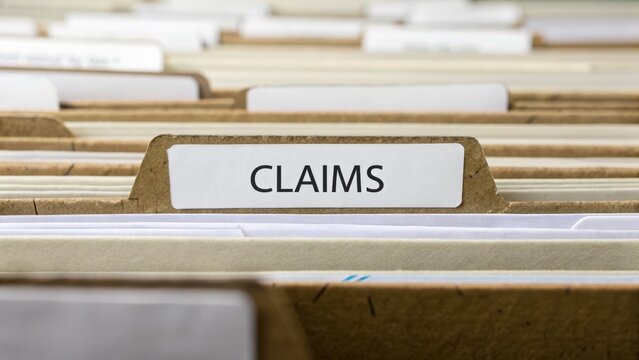 Close-Up View of File Folders Labeled Claims in an Office Setting