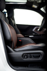 Modern car driver seat with electric seat adjustment controls inside vehicle interior.
