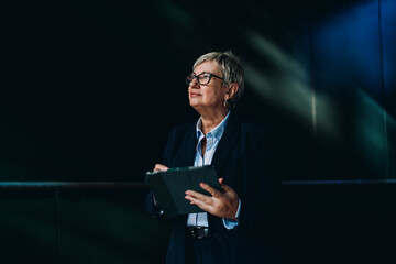 Side portrait of senior woman using tablet with confident smile. Modern metaphor for balance,...