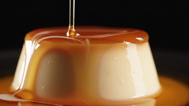 Close-up of silky smooth panna cotta dessert being drizzled with warm caramel sauce demonstrating textures and flowing liquids