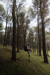 Fototapeta premium Photographer Standing Among Tall Pine Trees