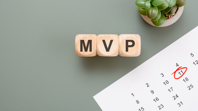 MVP Minimum Viable Product concept on wooden blocks. Startup launch, product development and agile management with calendar and succulent on a green desk.