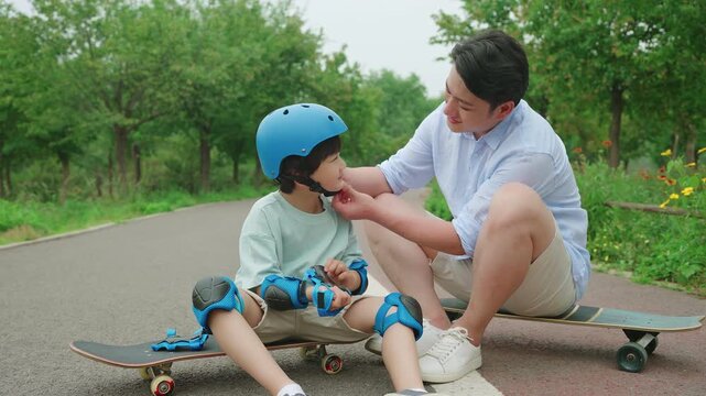 Dad assists his son with safety equipment before skateboarding