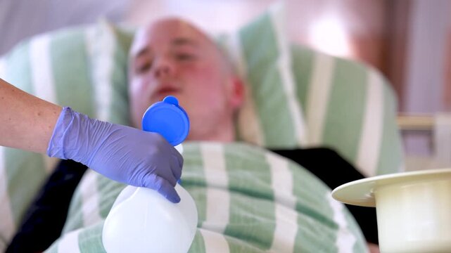Nursing staff shows urinary aids to hospitalized young male patient explaining toileting assistance during care
