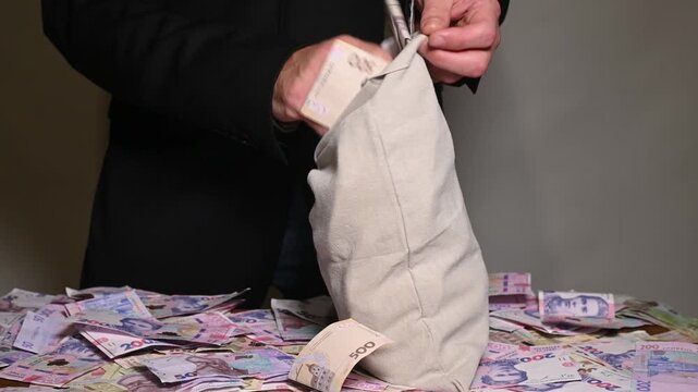 man frantically stuffs large sack of Ukrainian cash, stark representation of economic crime and corruption. secretive movement of illicit profits and stolen money, hiding cash hryvnia from authorities