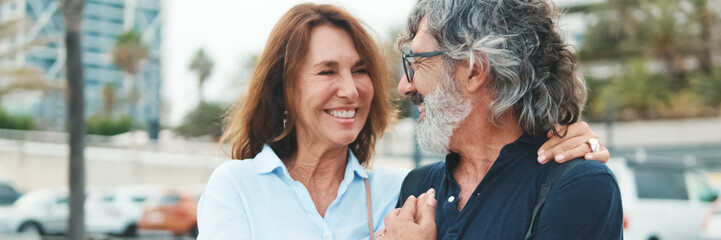 Close-up of an elderly couple standing on the embankment and looking at each other with smile....