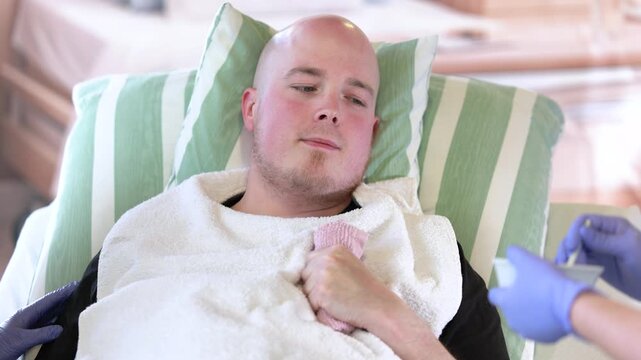 Nurse assisting male patient with neurological impairment during feeding, supportive dysphagia care in hospital