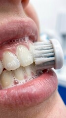 Obraz premium Close-up of a person brushing their teeth with an electric toothbrush.