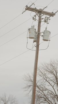 Utility power pole with transformers, insulators, cross-arm, wires. vertical video