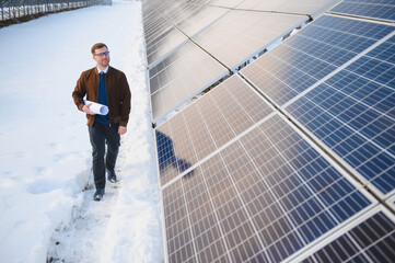 Engineer holding blueprint walking, inspecting solar panels