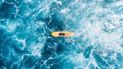 Woman on surfboard in blue ocean. Drone view of surfer during surfing © artifirsov