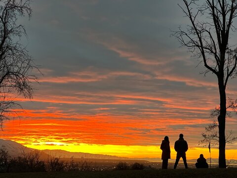 Rear view Silhouette of Three People at an observation point looking at an illuminated cityscape at sunset, Salt Lake City, Utah, USA