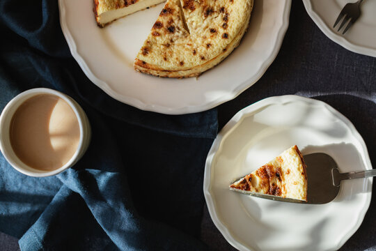 Close-up overhead view of a slice of Basque Burnt Cheesecake being served and  cappuccino on a table
