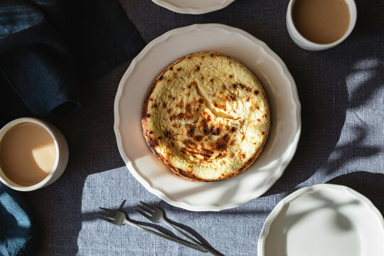 Close-up overhead view of a Basque Burnt Cheesecake on a table with two cappuccinos