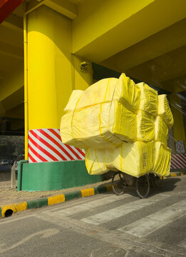 Close-up rear view of an Overloaded cycle rickshaw stacked with wrapped goods, New Delhi, India