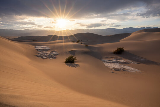 Sunburst at sunset over large sand dunes, Death Valley National Park, California, USA
