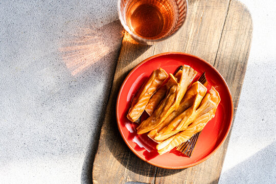 Overhead view of Smoked salmon fillets with a glass of apple cider vinegar on a wooden chopping board