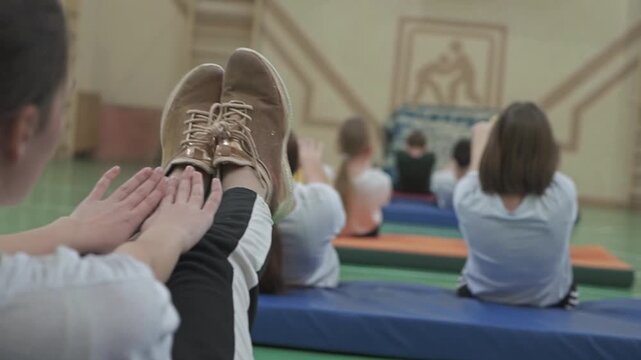 Young students practicing gymnastics with professional instructor, developing coordination and movement skills during physical education class in school